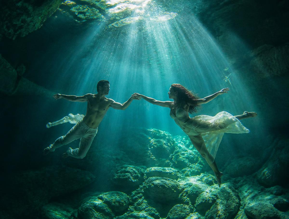 Two dancers suspended in a sunlit cenote